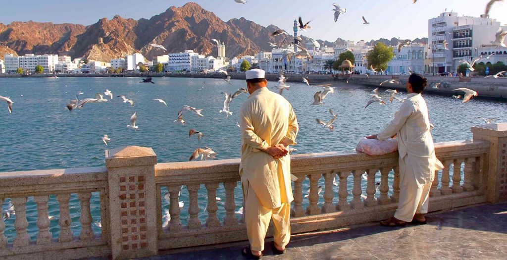 MUSCAT, OMAN - JANUARY 28, 2012: Locals feeding seagulls at Muttrah corniche with  Sur Al Lewatia Mosque in the background