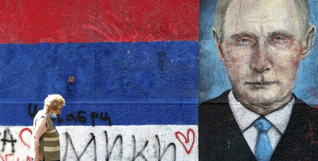 A woman wearing a mask to protect against the spread of coronavirus passes by graffiti depicting Russian President Vladimir Putin in Belgrade, Serbia, Wednesday, Aug. 19, 2020. Putin says that a coronavirus vaccine developed in the country has been registered for use and one of his daughters has already been inoculated. Speaking at a government meeting Tuesday, Aug. 11, 2020, Putin said that the vaccine has proven efficient during tests, offering a lasting immunity from the coronavirus. (AP Photo/Darko Vojinovic)