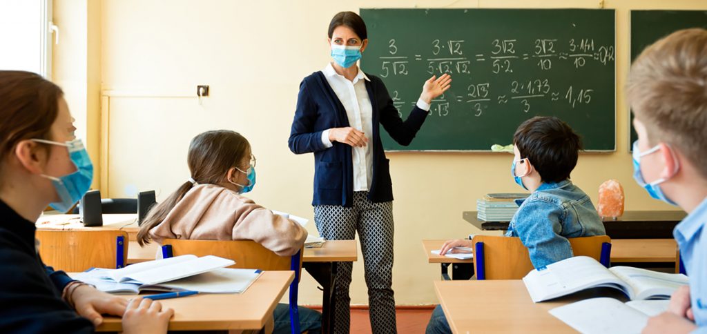 A teacher wearing a N95 Face masks teaches mathematics at an High School