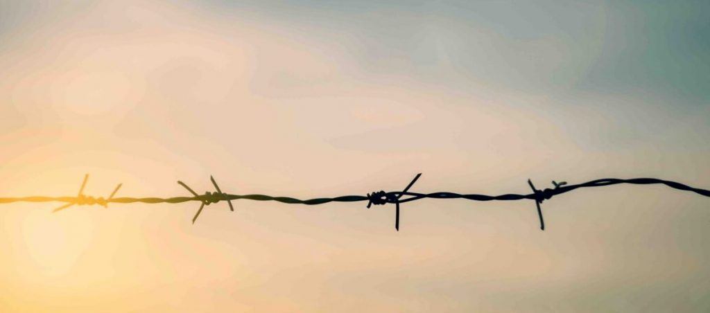 Barbed wire fence with sunset Twilight sky. Chain spike for world war safe security boundary concept for human rights slave, prison hostage hope to peace. International liberty day. russia ukraine